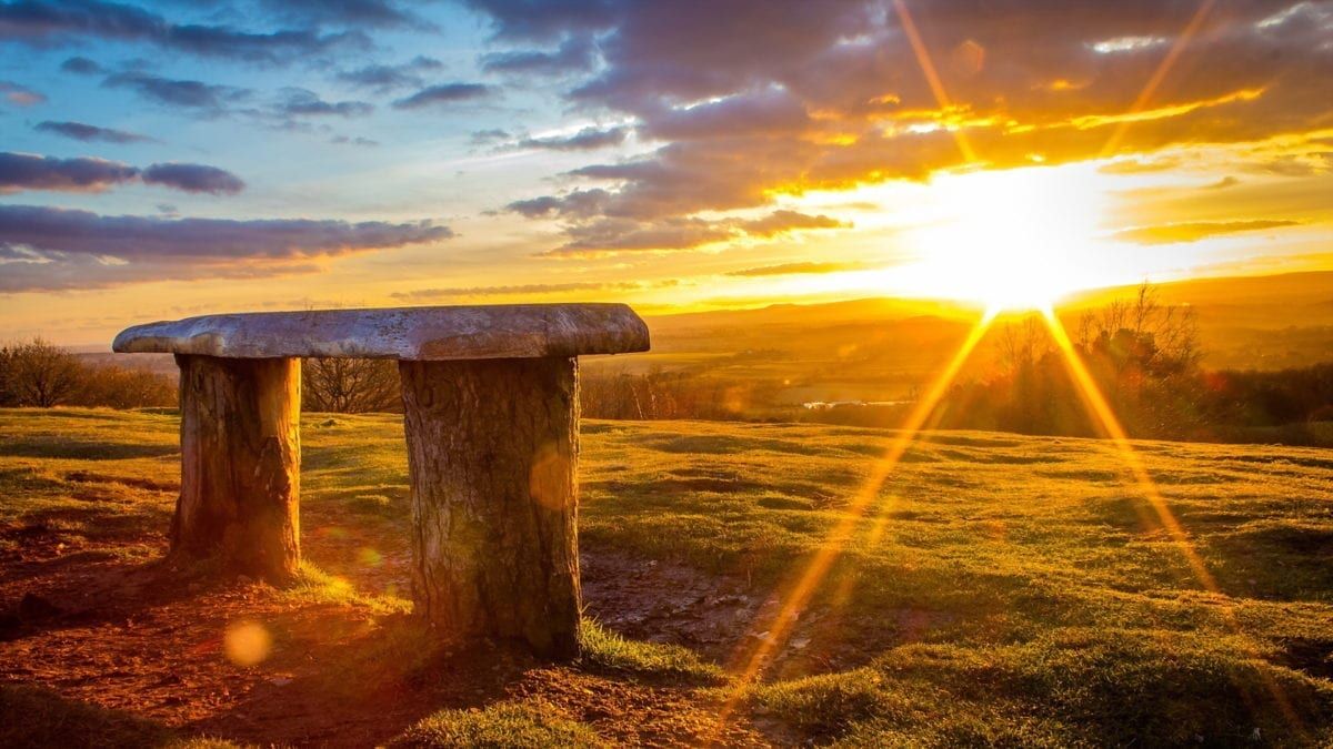 Image of a bench with a bright sun in the distance