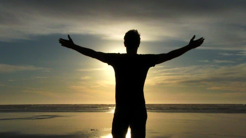 Image of a guy looking at the ocean with his arms wide open