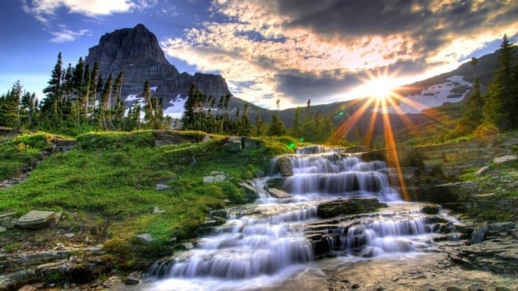 Image of a waterfall surrounded by forest and mountains